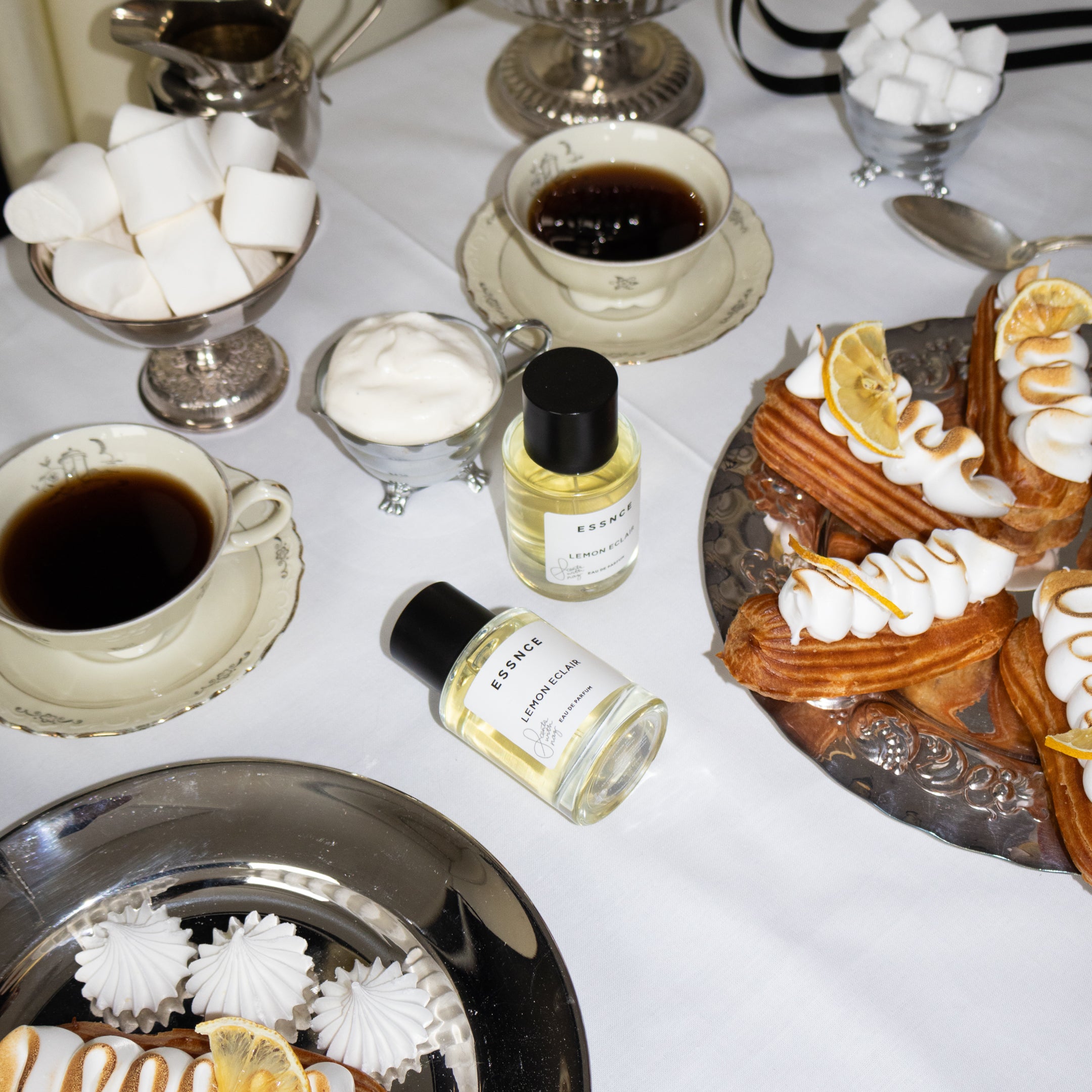 Fotografering på Lemon Eclair parfym från ESSNCE. Ett bord uppdukat med kaffe och bakelser med porslin. 